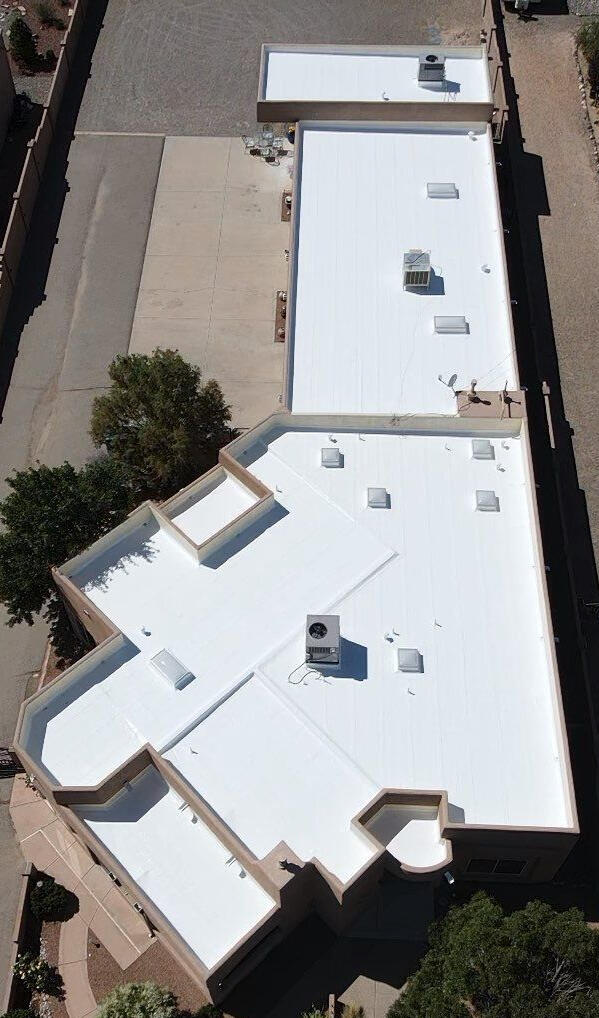 A residential flat roof in Albuquerque, New Mexico, coated with white silicone and featuring many skylights for enhanced natural lighting.