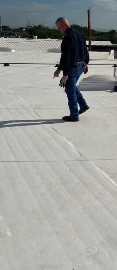 Male insurance adjuster on a flat TPO (Thermoplastic Polyolefin) roof in Albuquerque, New Mexico, inspecting the roof system for an insurance claim evaluation.
