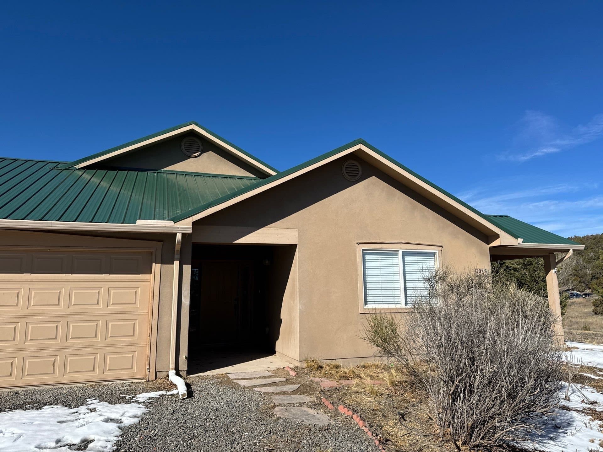 A finished green metal roof on a New Mexico stucco home by Paramount Roofing
