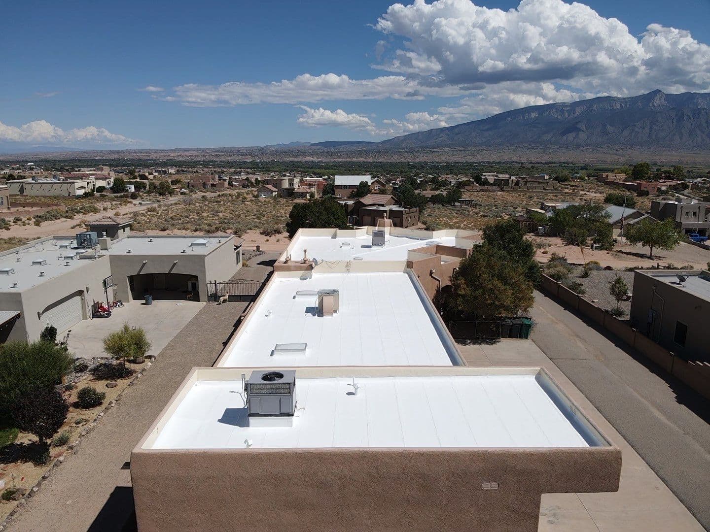 Freshly coated white flat roof on a Rio Rancho home with the Sandia Mountains behind it