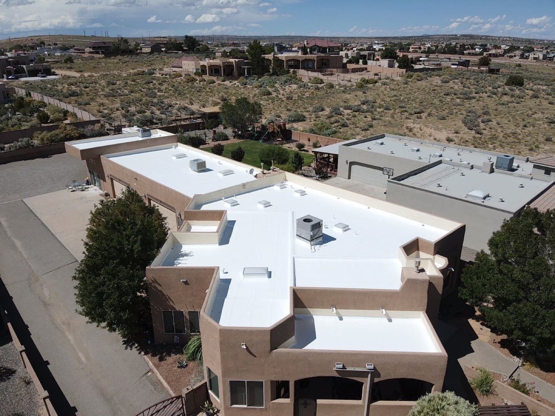 Aerial view of a finished bright-white flat roof on a Rio Rancho home in the New Mexico desert