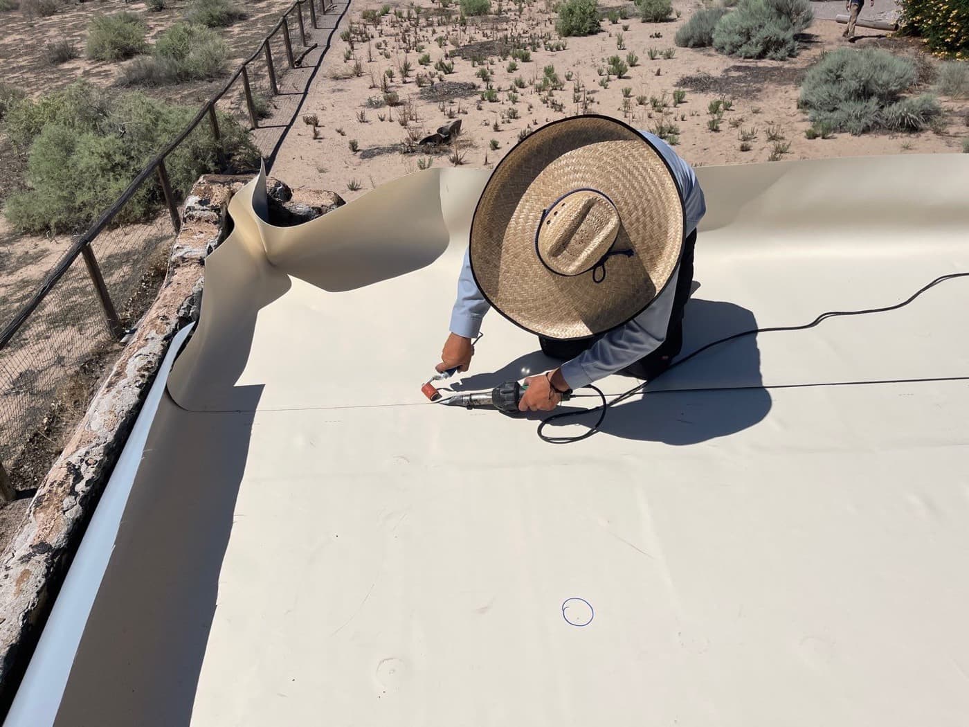 A Paramount Roofing technician installing a flat roof on a home in the New Mexico desert