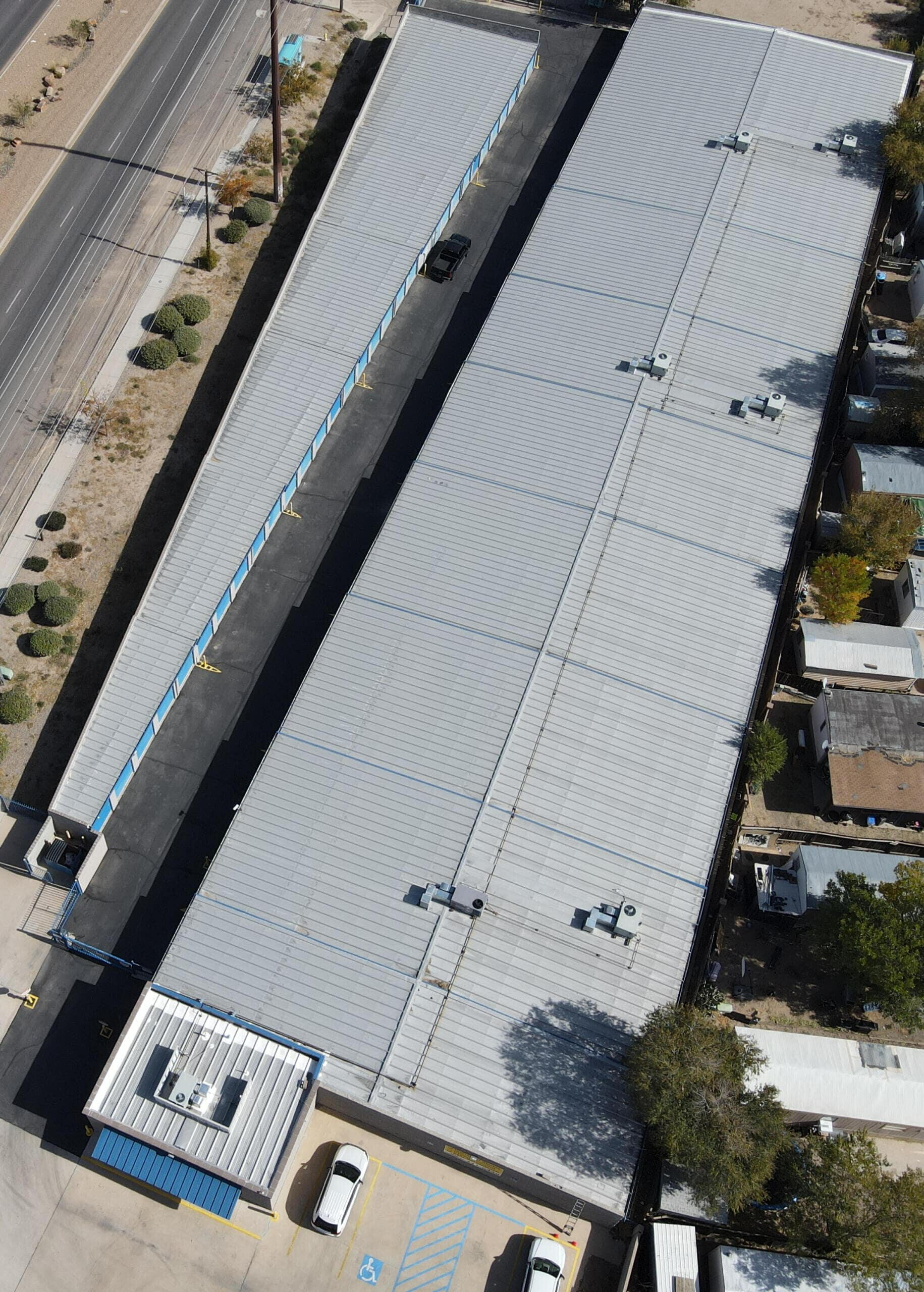 Repair work in progress on a metal roof of a large commercial storage facility located in Albuquerque, New Mexico.
