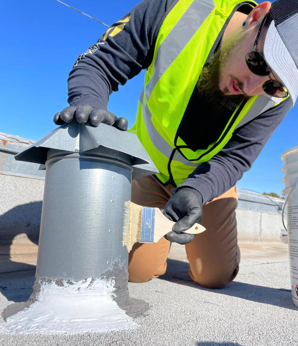 Paramount Roofing employee conducting a repair on a vent located on a flat roof in Albuquerque, New Mexico, demonstrating expertise in maintenance.
