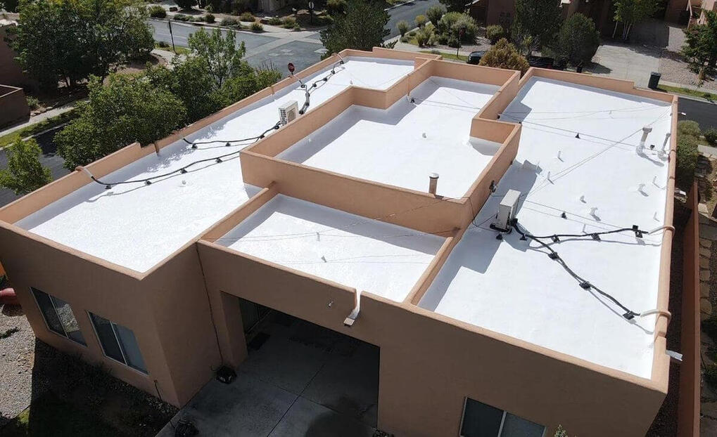 Drone shot from above capturing a newly applied white silicone roof coating on a flat residential roof in Albuquerque.