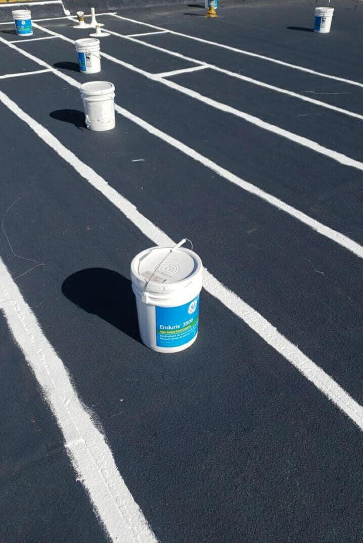 Repair process on a flat residential roof in Albuquerque, New Mexico, featuring a modified bitumen roof system. Seams are being resealed with silicone mastic to address areas causing leaks.