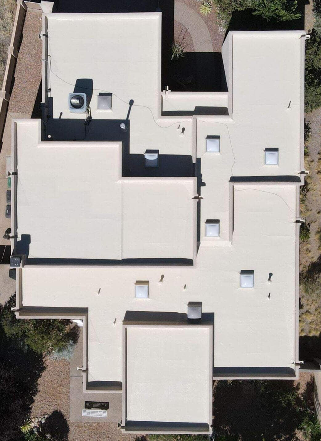 Drone image of a large flat residential roof in Albuquerque, New Mexico, restored with a silicone coating and featuring many skylights.